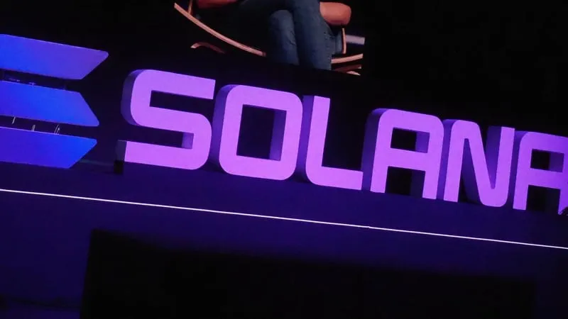 Large purple Solana letters and logo lit up on a conference stage