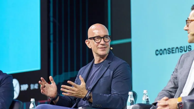 A speaker gesturing on stage during a panel at the Consensus conference